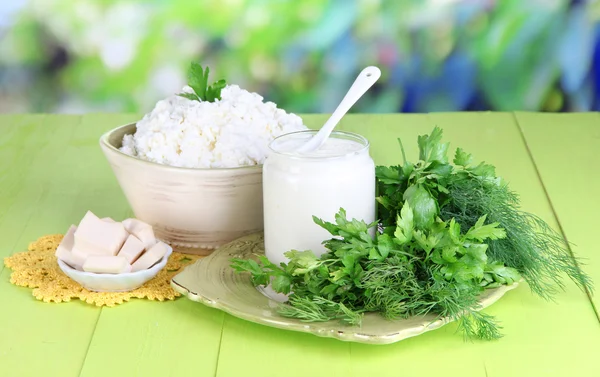 Productos lácteos frescos con verduras sobre mesa de madera sobre fondo natural — Foto de Stock