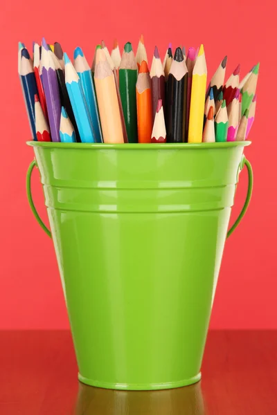 Кольорове відро з різнокольоровими олівцями на кольоровому фоні — стокове фото