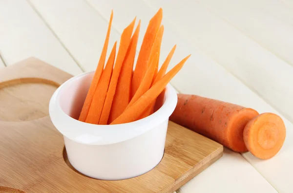 Яскрава свіжа морква, вирізані скибочки в мисці на дерев'яному столі крупним планом — стокове фото
