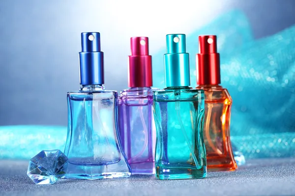 妇女在蓝色背景上的美丽瓶中的香水 — 图库照片