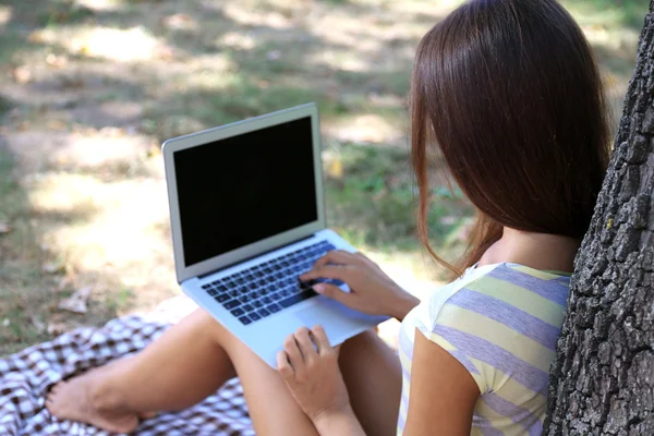 Vacker ung flicka med laptop i park — Stockfoto