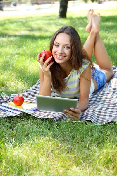 Beautiful young girl with tablet in park — Stock Photo, Image