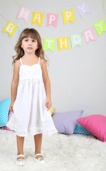 Little girl dancing on bed in room on grey wall background — Stock Photo, Image