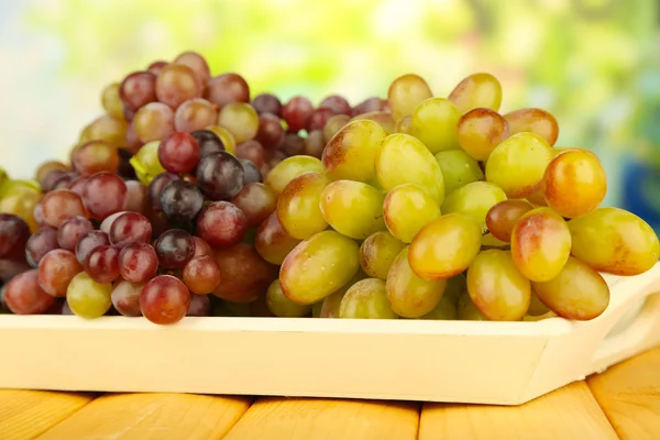 Fresh grape on wooden tray on bright background — Stock Photo, Image