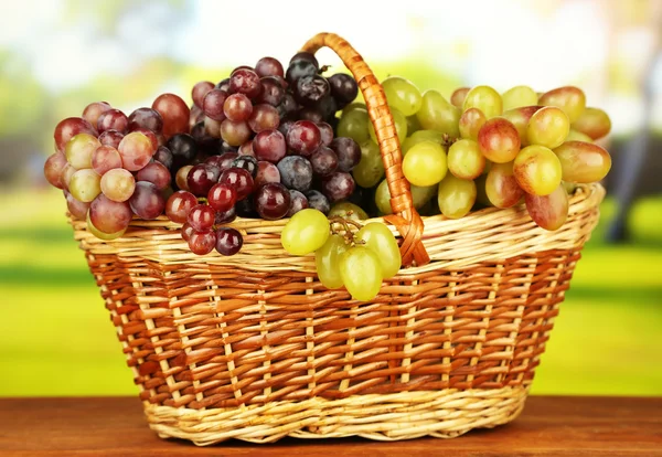 Fresh grape on wicker mat on bright background — Stock Photo, Image