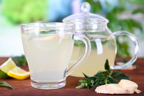 Wasserkocher und Tasse Tee mit Ingwer auf Holztisch auf Naturhintergrund — Stockfoto