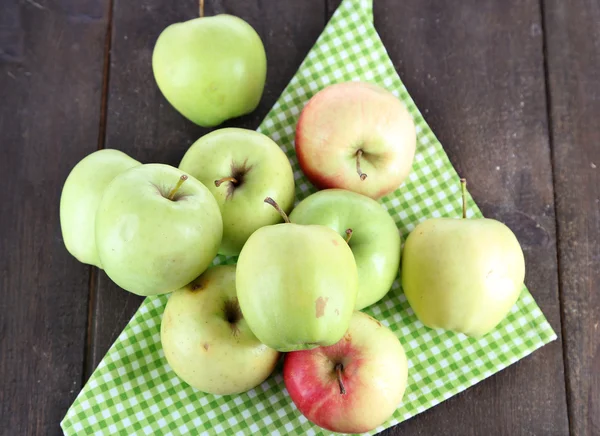 Juicy apples on napkin on wooden table — Stock Photo, Image