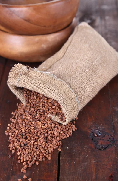 Doek zak met boekweit gries en kommen op houten achtergrond — Stockfoto