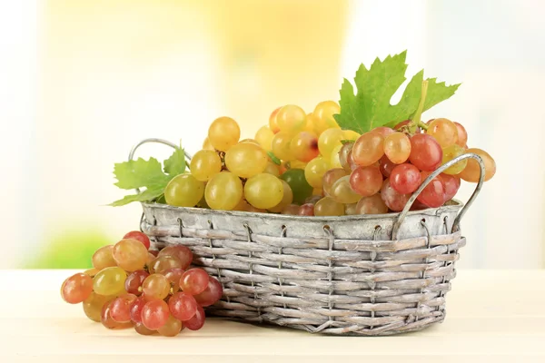 在木桌上，自然背景上的篮子里成熟甜葡萄 — 图库照片