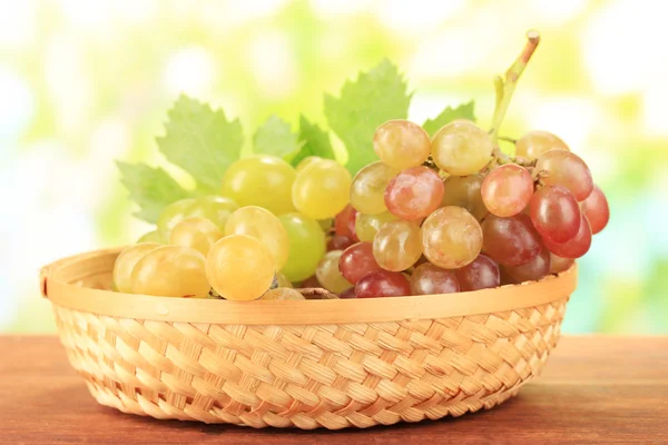 Ripe sweet grape in basket on wooden table, on nature background — Stock Photo, Image