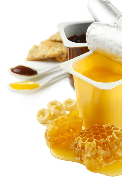 Tasty desserts in open plastic cups and honey combs, isolated on white — Stock Photo, Image