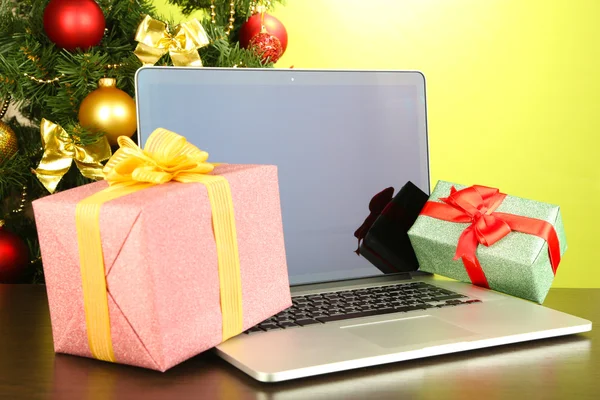 Laptop with gifts on table on green background — Stock Photo, Image