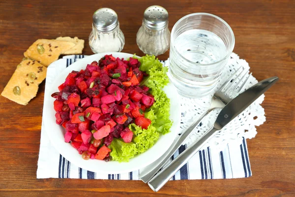 Свекольный салат на тарелках на салфетках на деревянном столе — стоковое фото
