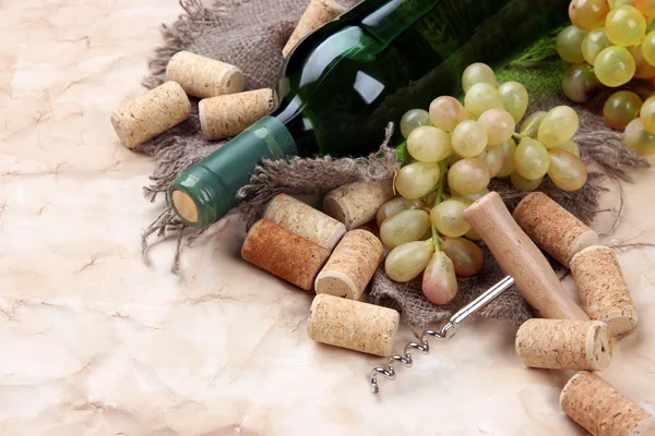 Botella de vino, uvas y corchos sobre papel viejo — Foto de Stock