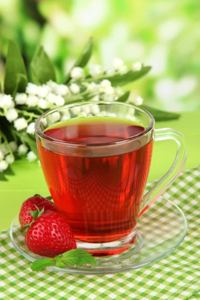 Delicious strawberry tea on table on bright background