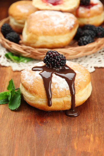 Tasty donuts with chocolate and berries on wooden table — Stock Photo, Image