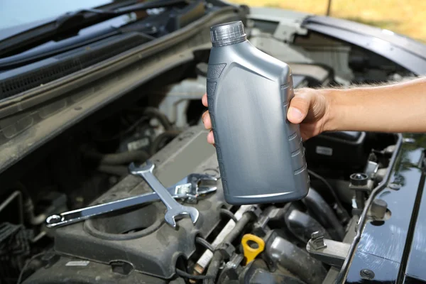 Auto mechanic hand holding motor oil — Stock Photo, Image