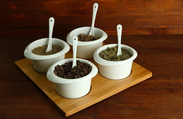 Assortment of spices in white bowls, on wooden background — Stock Photo, Image