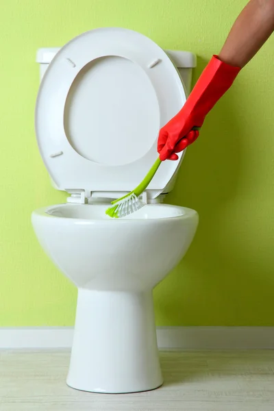 Woman hand with brush cleaning a toilet bowl in a bathroom — Stock Photo, Image