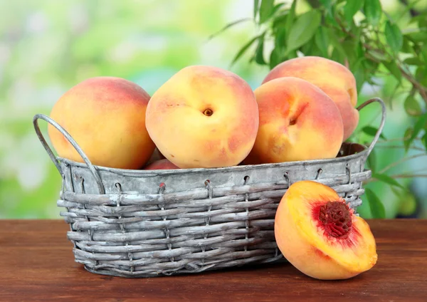 Ripe sweet peaches in wicker basket, on bright background — Stock Photo, Image
