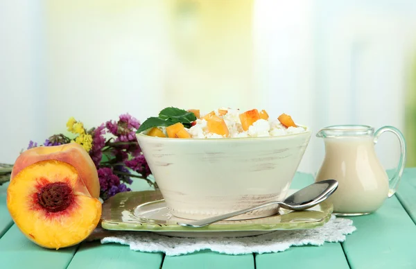 Sour cheese and pieces of fresh peach,on wooden table, on light background — Stock Photo, Image