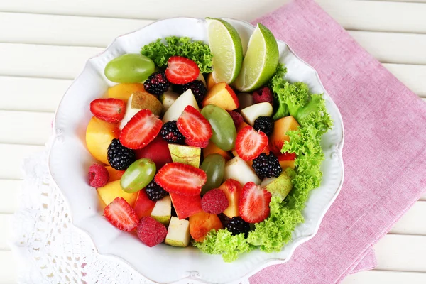 Salade de fruits dans une assiette sur une serviette de table en bois — Photo