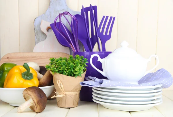 Plastic kitchen utensils in cup on wooden table — Stock Photo, Image