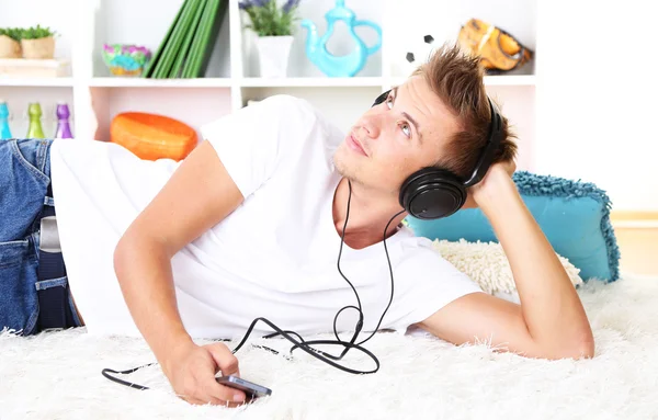 Hombre joven relajándose en la alfombra y escuchando música — Foto de Stock