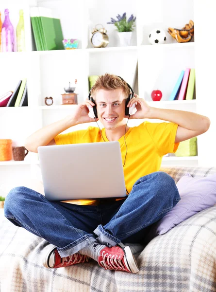 Jeune homme relaxant sur canapé avec ordinateur portable — Photo