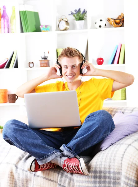 Jovem relaxante no sofá com laptop — Fotografia de Stock