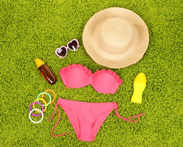 Swimsuit and beach items on green background — Stock Photo, Image