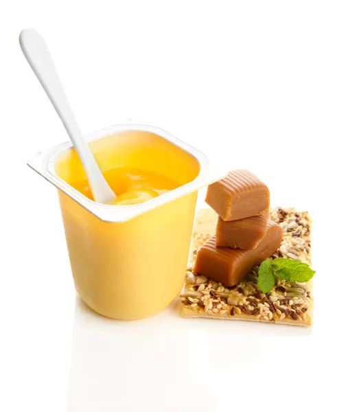 Sabroso yogur en taza de plástico abierta, galletas y caramelos de caramelo aislados en blanco —  Fotos de Stock