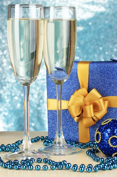 Бокалы шампанского с подарочной коробкой на блестящем фоне — стоковое фото