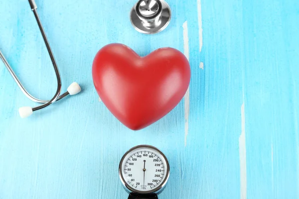 Tonometer, stethoscope and heart on wooden table close-up — Stock Photo, Image