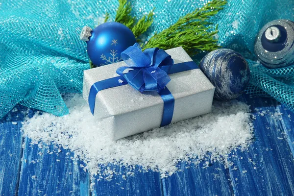 Composizione con palline di Natale, confezione regalo e neve su sfondo di legno a colori — Foto Stock