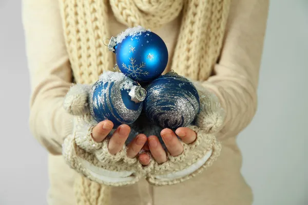 Mani femminili in guanti Albero di Natale palle, su sfondo di colore — Foto Stock