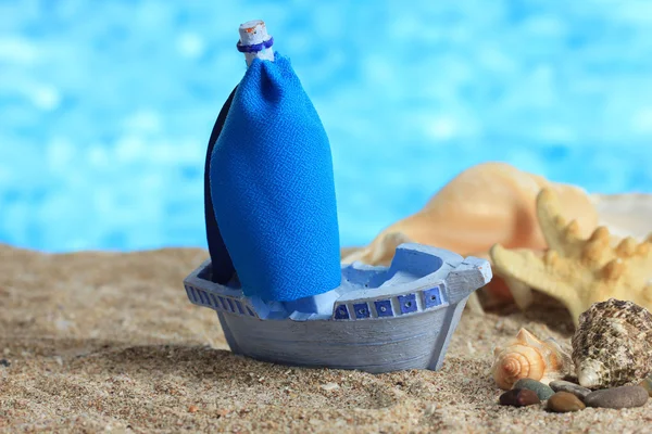 Bateau jouet bleu sur sable, sur fond bleu — Photo