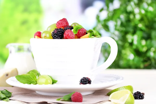 Fruit salad in cup on wooden table on nature background Royalty Free Stock Images
