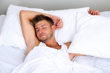 Yakışıklı genç adam yatakta.