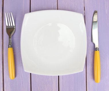 Plate and cutlery on wooden table close-up