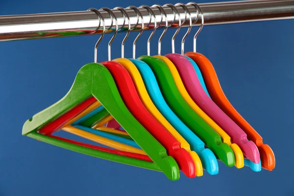 Cabides de roupas coloridas no fundo azul — Fotografia de Stock