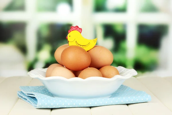 Jaja w płycie na drewnianym stole na tle okna — Zdjęcie stockowe