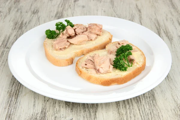 Leckere Sandwiches mit Thunfisch und Lebertran auf weißem Teller. auf Holzgrund — Stockfoto