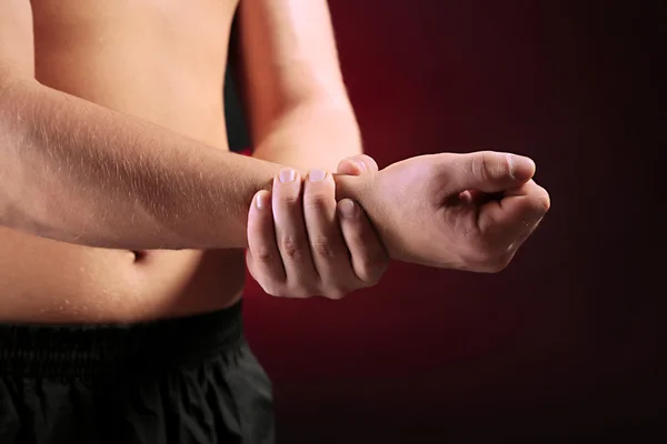 Junger Mann mit Schmerzen in der Hand, auf rotem Hintergrund — Stockfoto