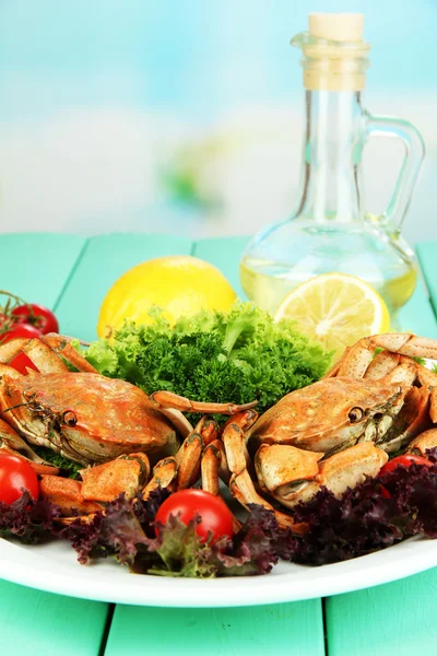 Gekookte krabben op wit bord met salade bladeren en tomaten, op houten tafel, op lichte achtergrond — Stockfoto