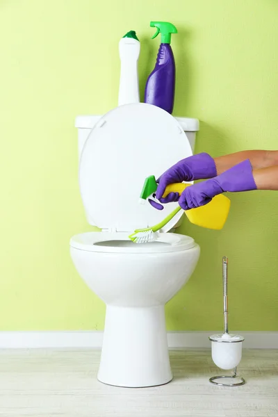 Mano de mujer con botella de spray limpiando un inodoro en un baño —  Fotos de Stock