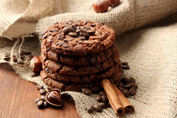 Homemade cookies with sesame seeds, chocolate, on wooden table, on sackcloth background — Stock Photo, Image