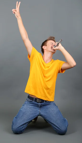 Guapo joven canta sobre fondo gris — Foto de Stock