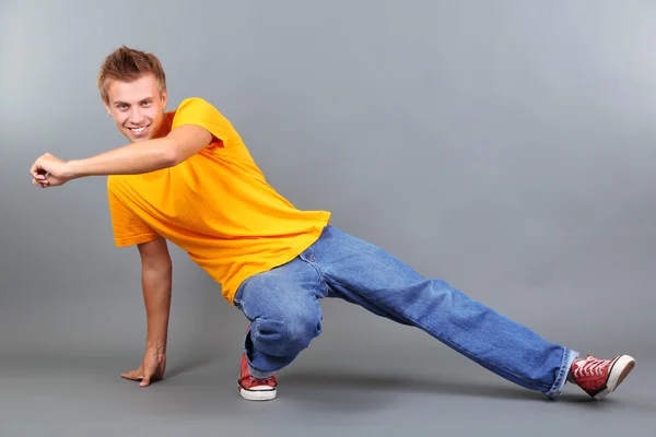 Knappe jongeman dansen op grijze achtergrond — Stockfoto