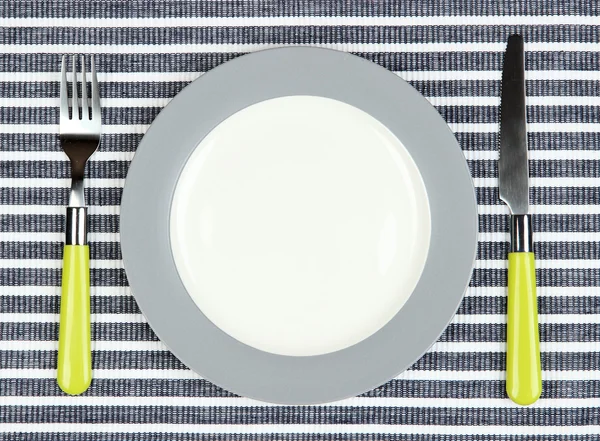 Cuchillo, placa de color y tenedor, sobre fondo de color —  Fotos de Stock